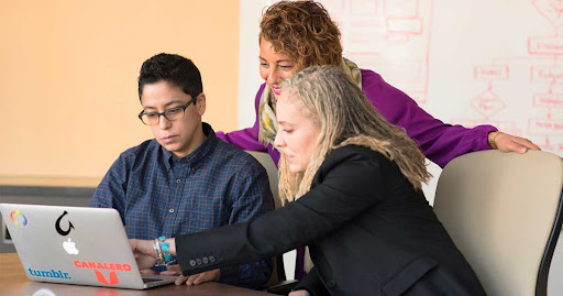 Group of people looking at a computer trying choose among the best chatbot platforms